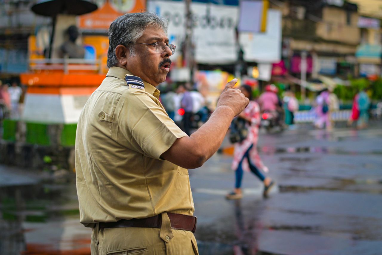 A traffic police officer directing vehicles on a bustling street in Kolkata, India.