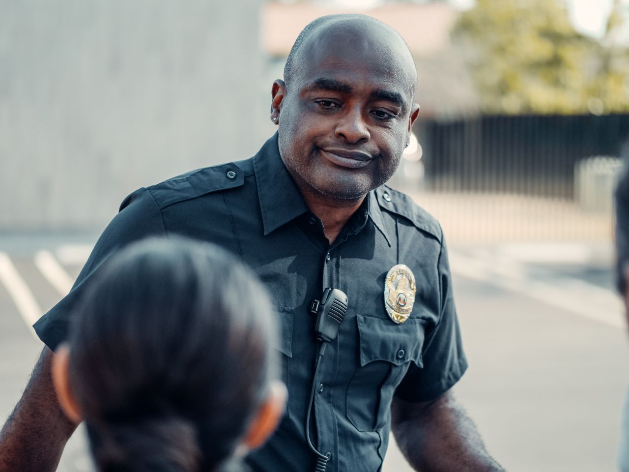 A police officer in uniform engaging warmly with people outdoors.